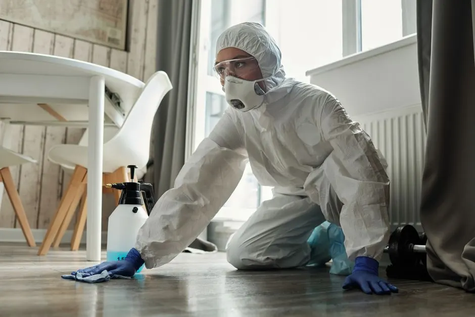 Person in full protective suit cleaning a floor, showcasing safety measures.